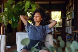 Woman Relaxing In Plant Filled Home